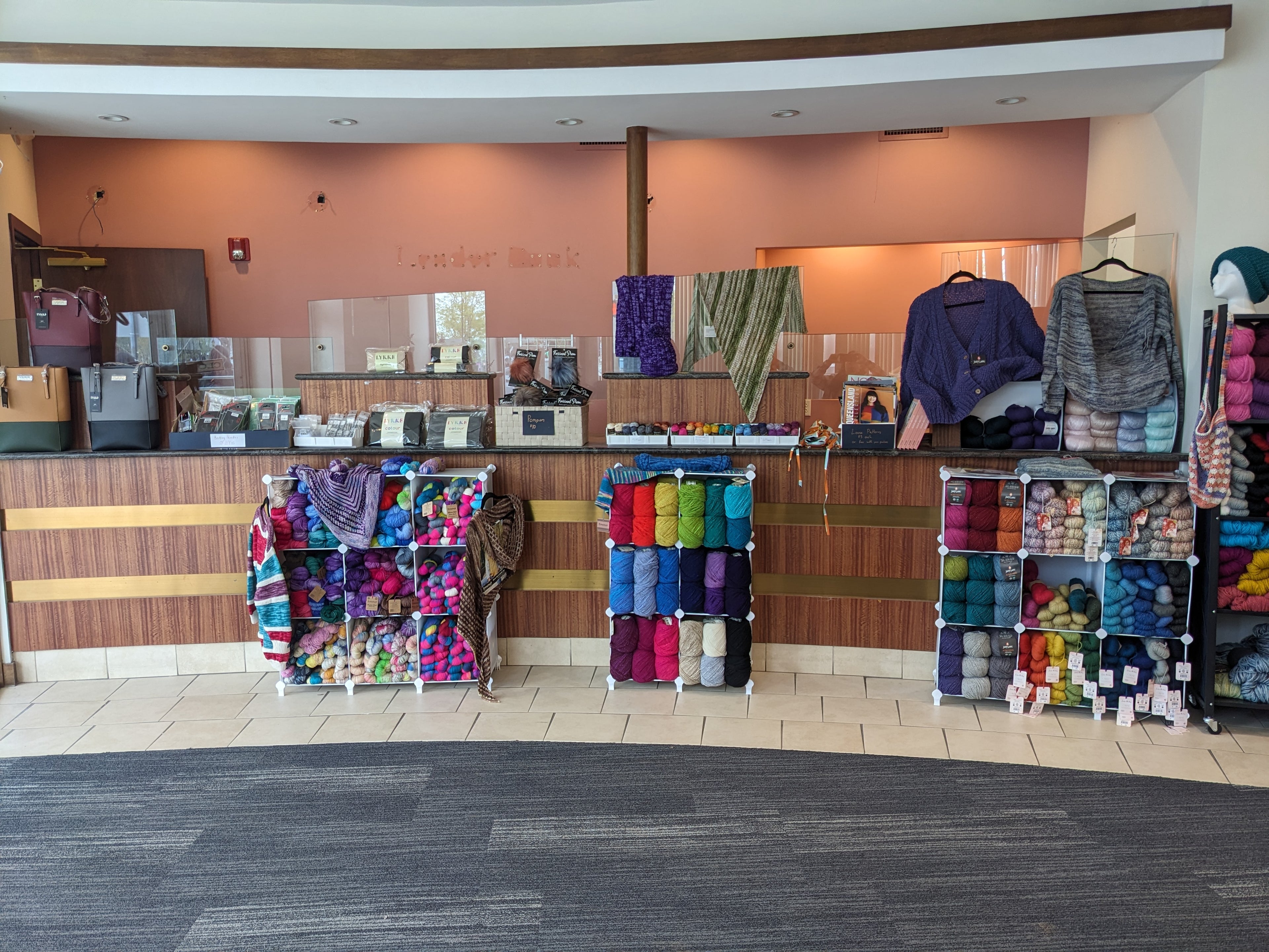 Image of Mind's Eye Yarn's current location. Shelves of yarn stacked neatly against a bank's teller windows.